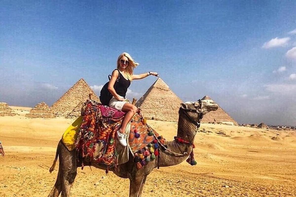 Una mujer montando un camello frente a las pirámides