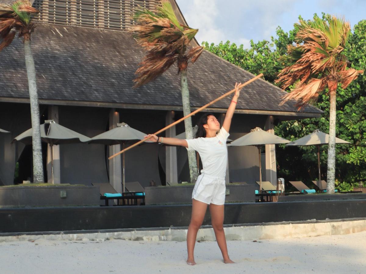 一名女子手持一根棍子站在海滩上