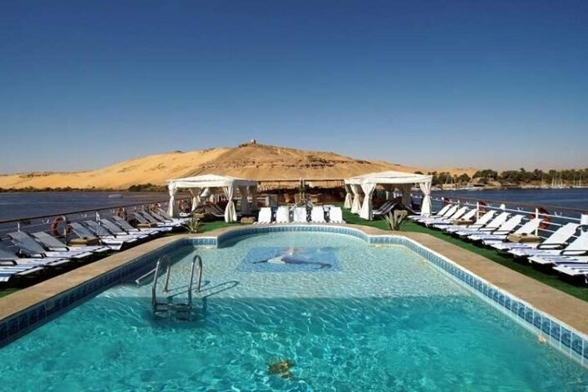 a swimming pool with chairs and a mountain in the background
