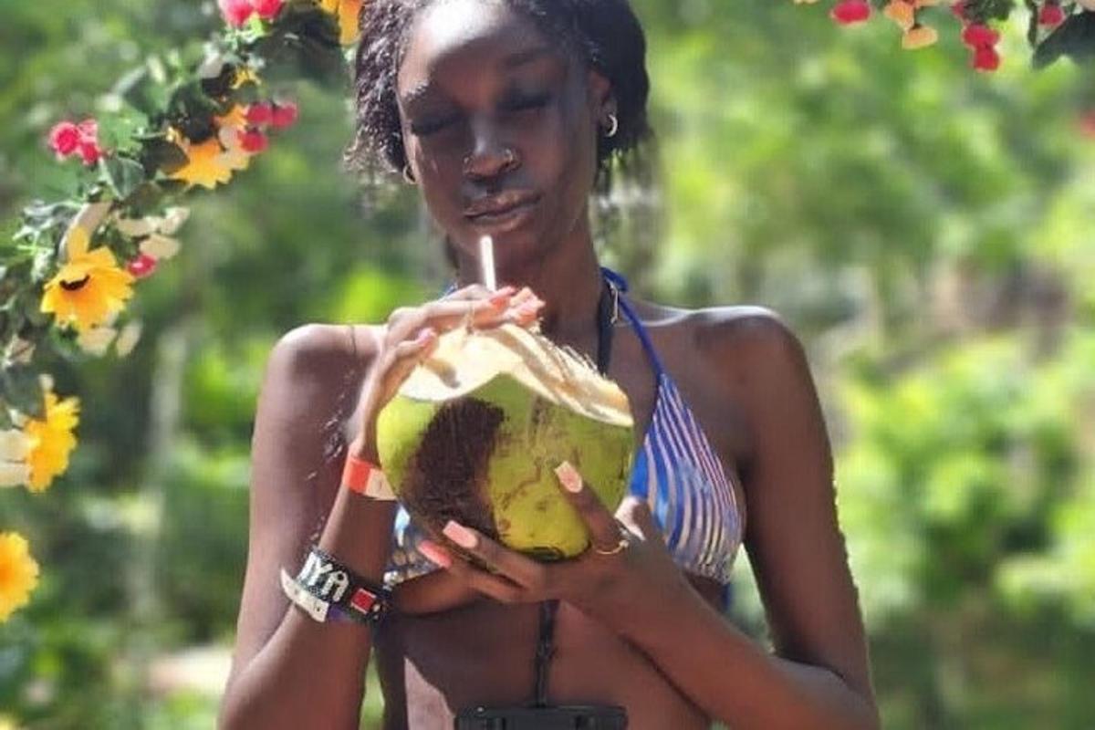 una dona sosté una beguda en un coco