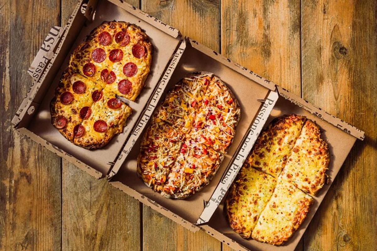 tre pizze in scatola su un tavolo di legno