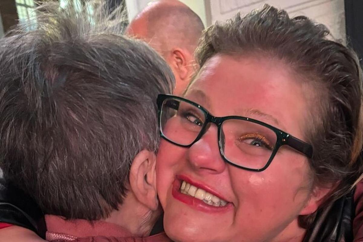 a woman with glasses is hugging a man