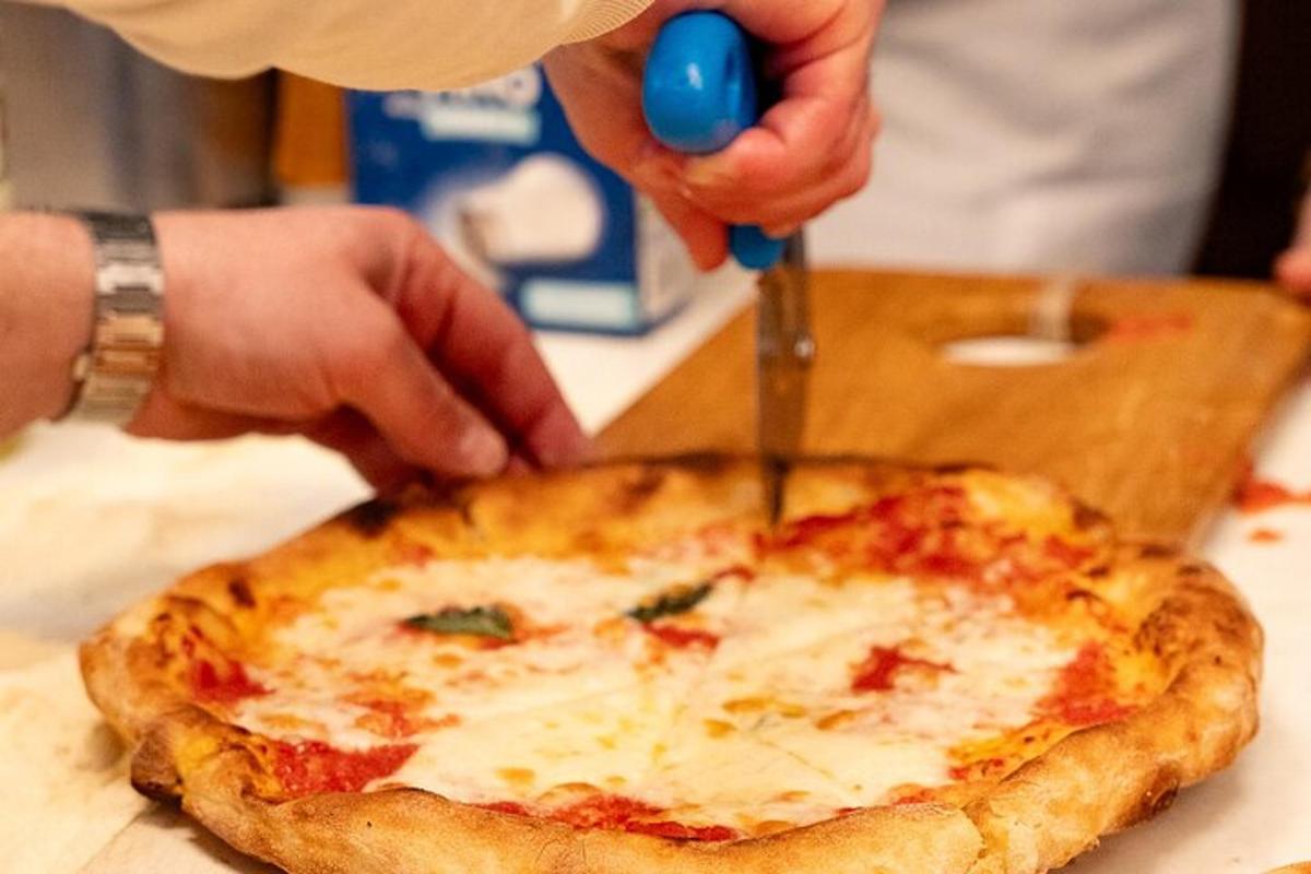 uma pessoa cortando uma pizza com uma tesoura