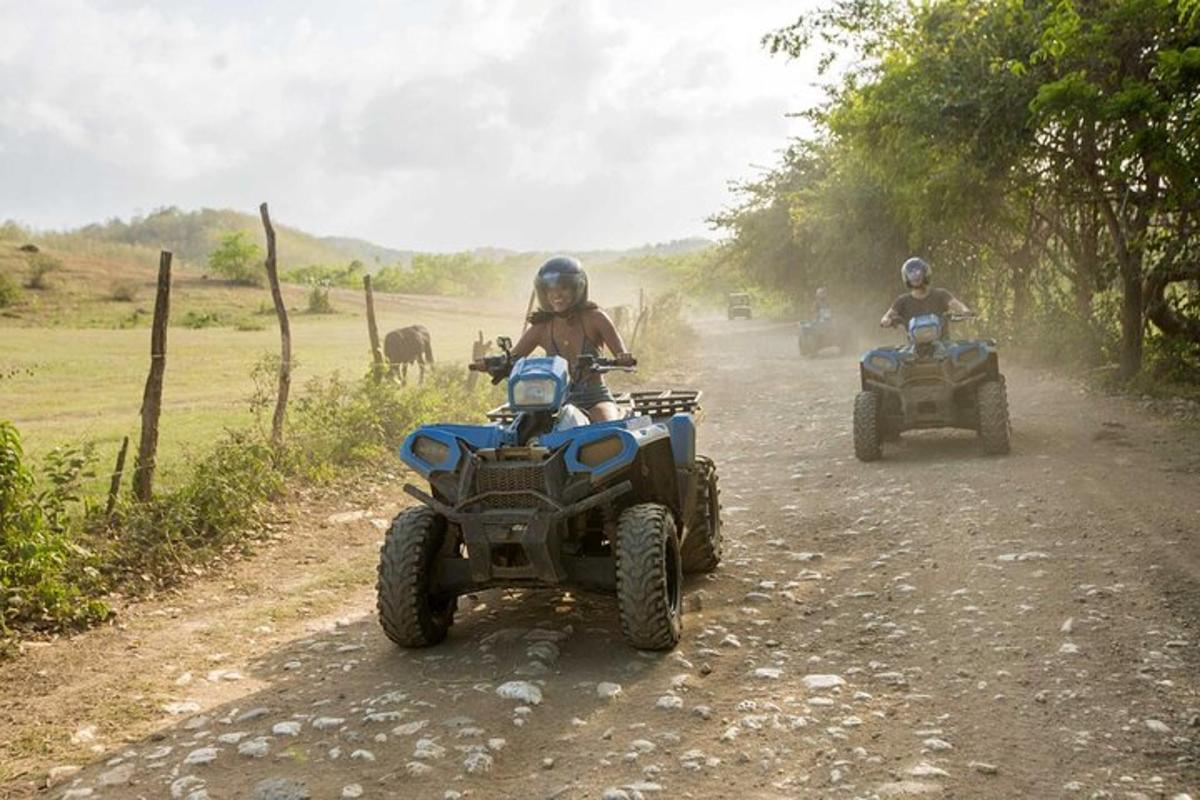 two people riding on atvs on a dirt road