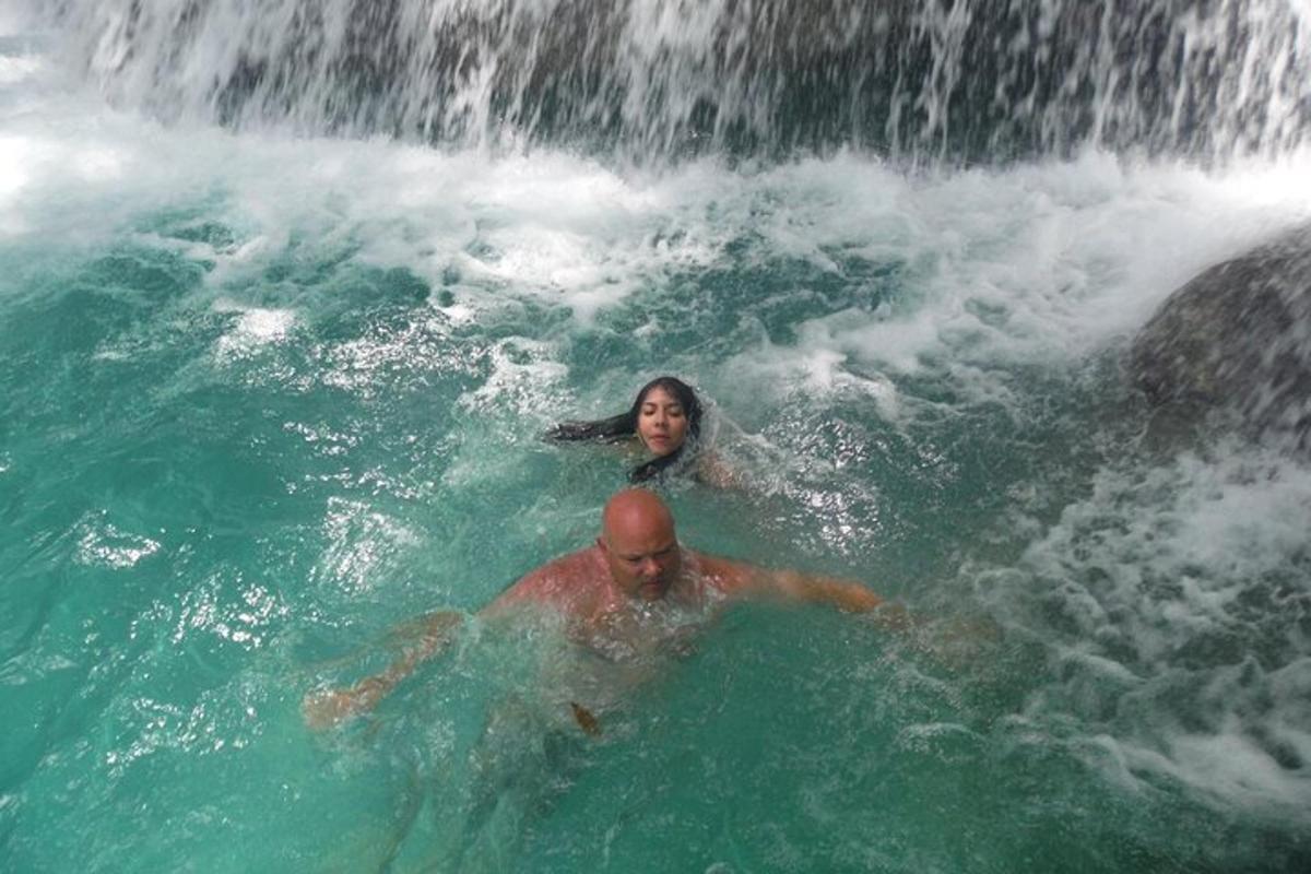 a man and woman swimming in a waterfall