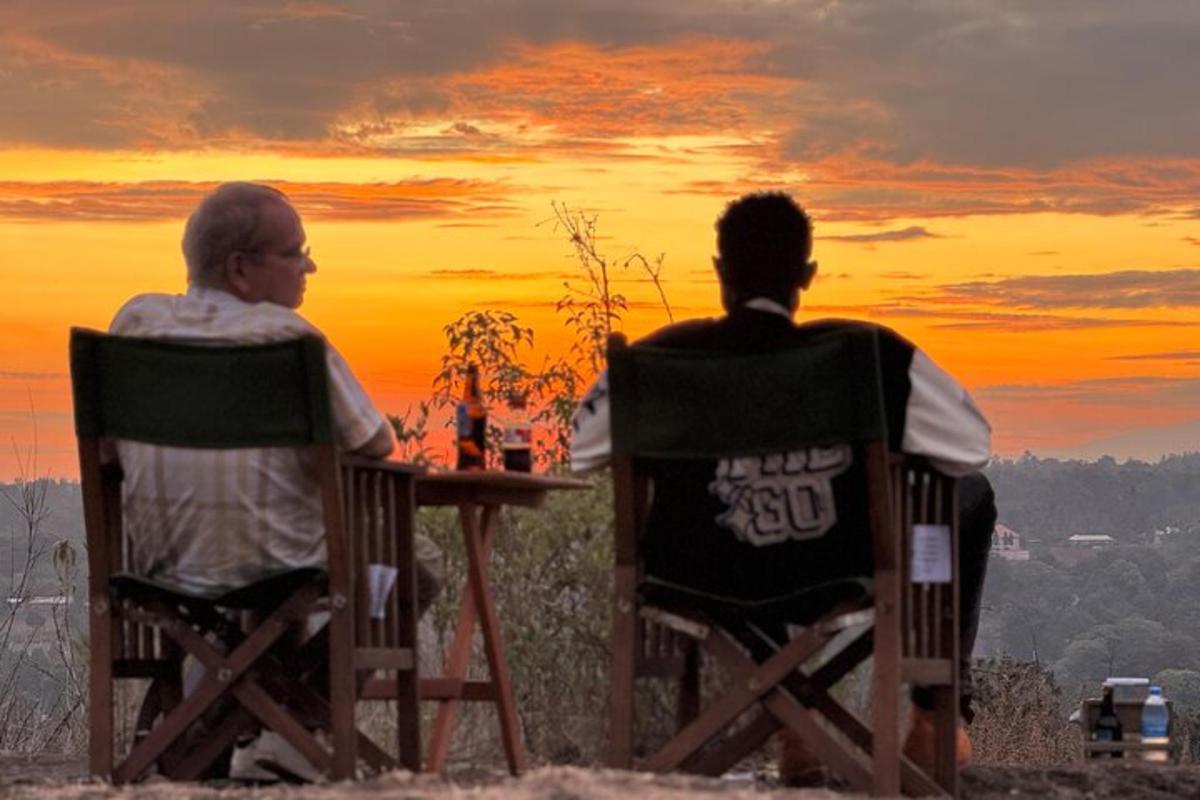 two men sitting at a table watching the sunset