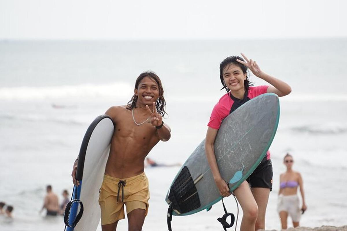 dua pemuda berjalan di pantai dengan papan selancar