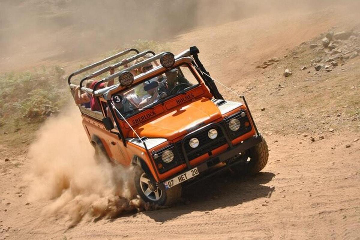 Un jeep naranja circulando por un camino de tierra