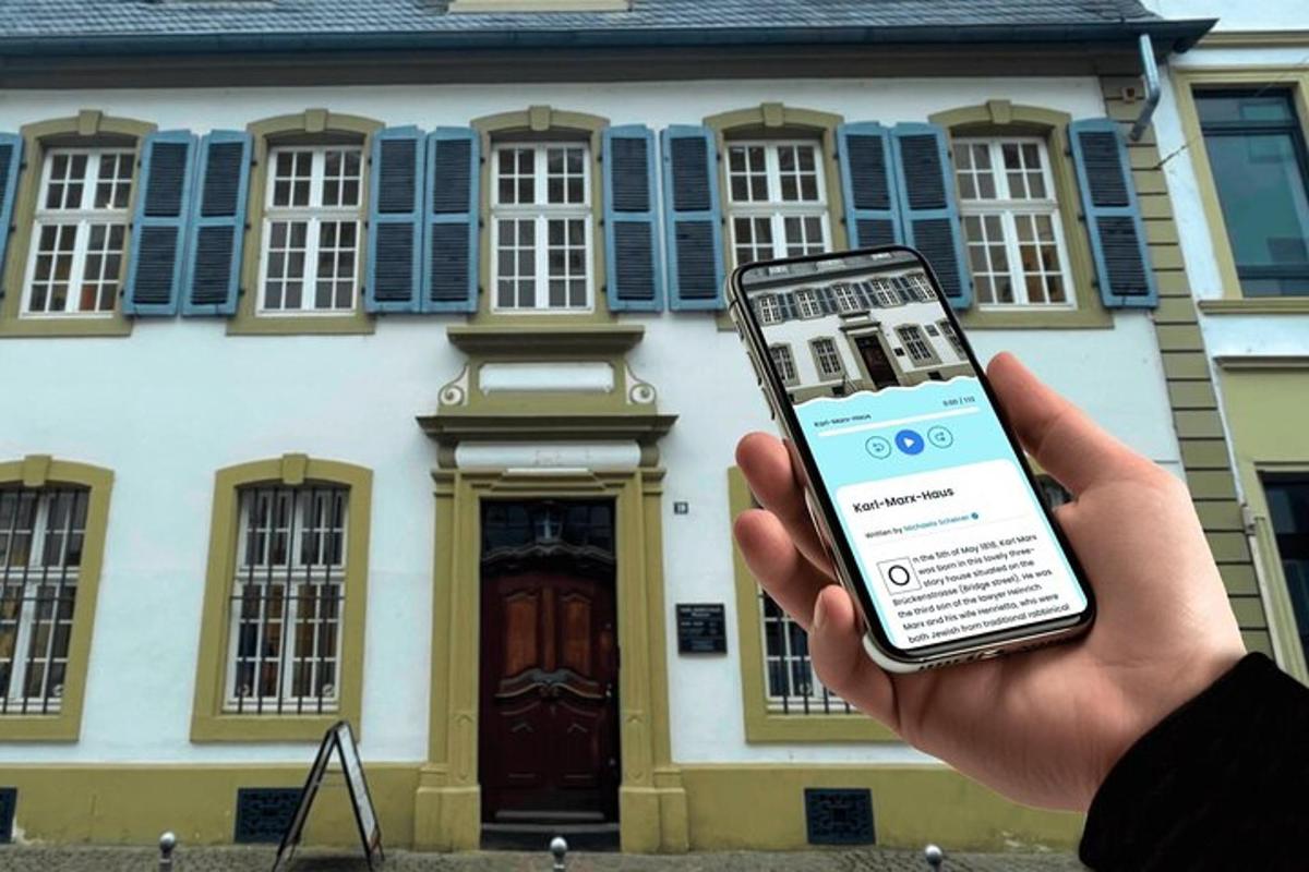 egy személy a kezében egy mobiltelefon egy ház előtt