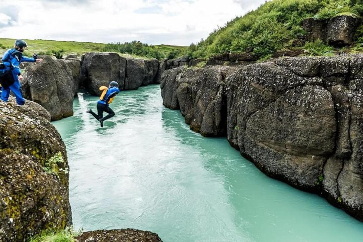 zwei Menschen springen zwischen zwei Felsen in einen Fluss