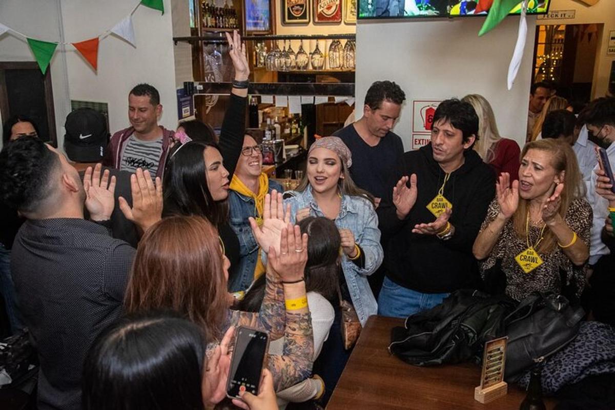 ellerini kaldırmış bir barın etrafında oturan bir grup insan