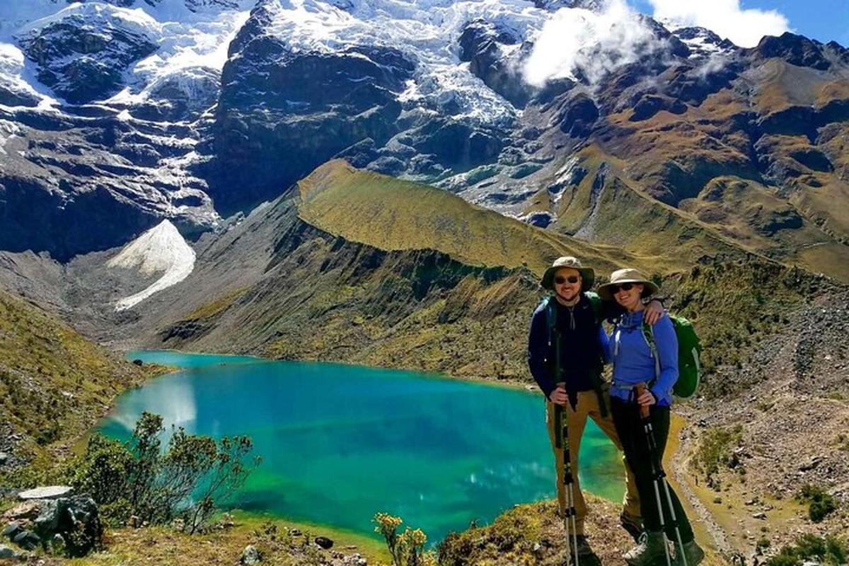 dues persones dempeus al cim d'una muntanya amb un llac