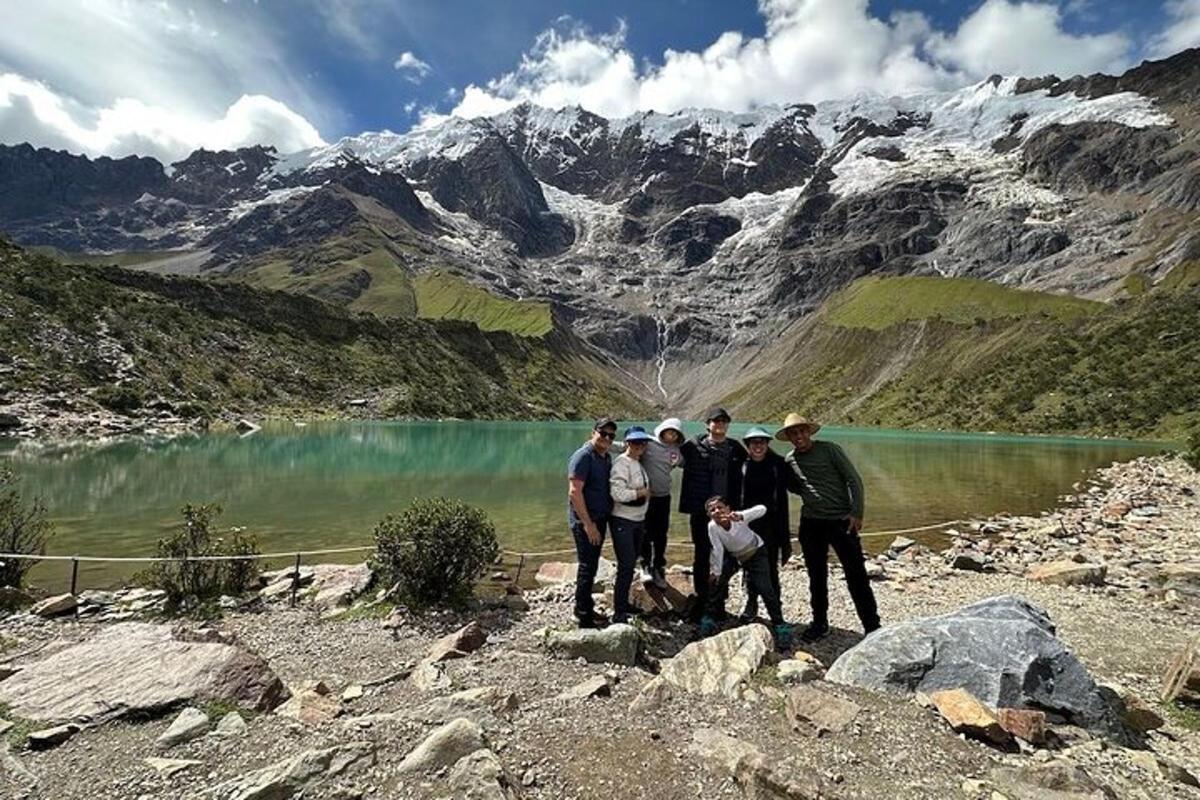 un grup de persones dempeus a prop d'un llac de muntanya