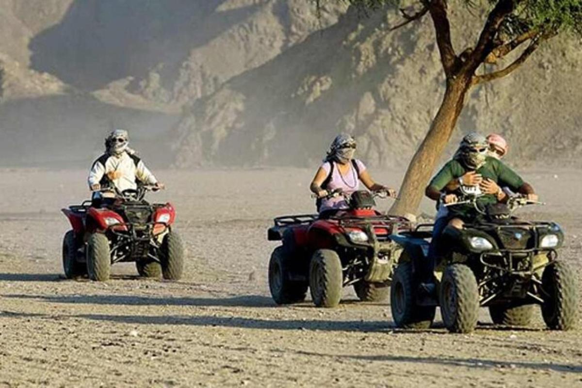 tre persone in sella a quad nel deserto