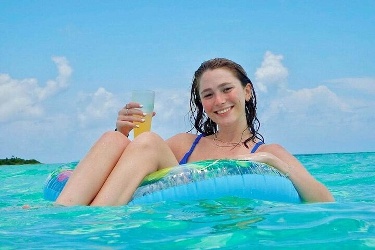 一个女孩坐在水中的木筏上，喝着饮料