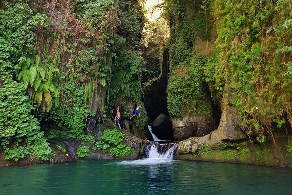 dua orang berdiri di hadapan air terjun di sungai