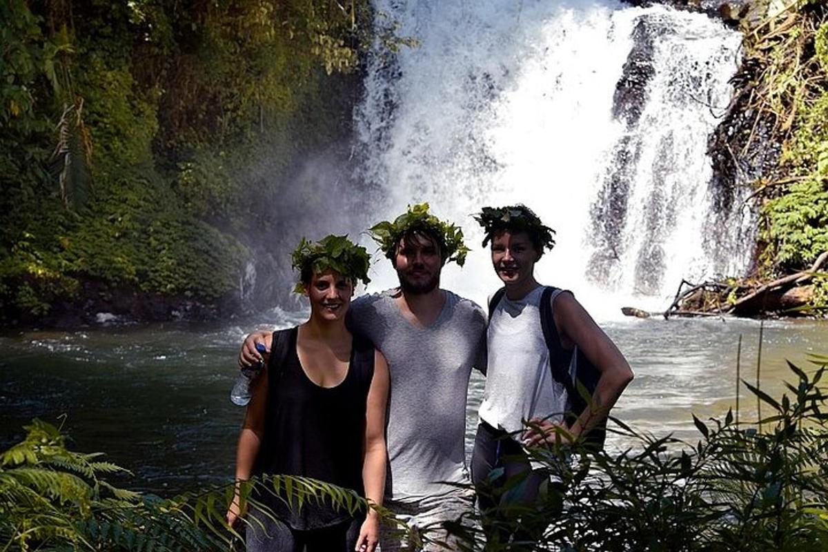 tiga orang berdiri di hadapan air terjun