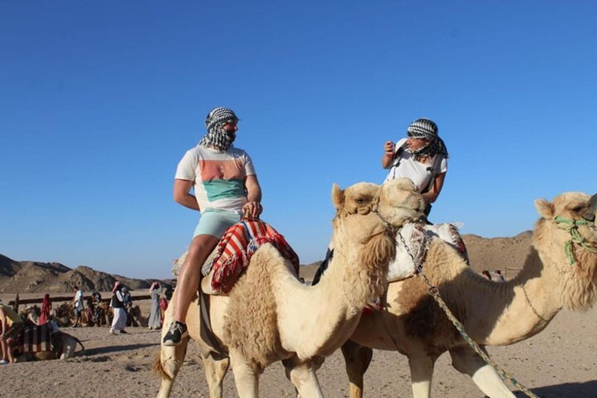 zwei Personen reiten auf einem Kamel in der Wüste