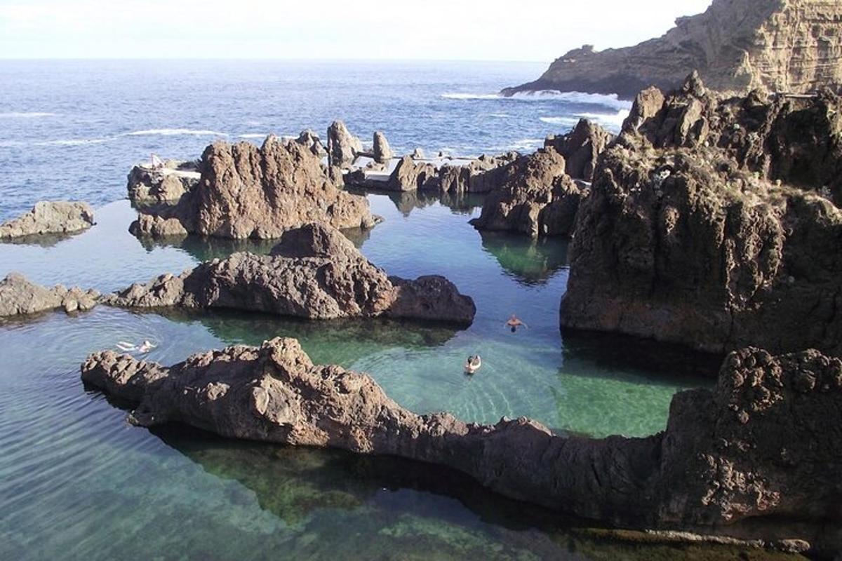 a group of people swimming in a rock pool in the ocean