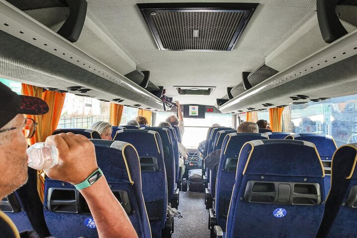 cilvēks sēž autobusā ar dzērienu