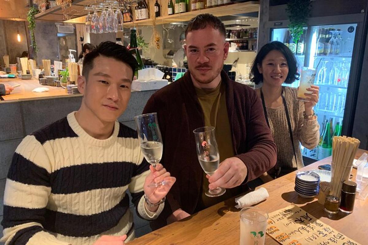 dois homens sentados à mesa segurando taças de vinho
