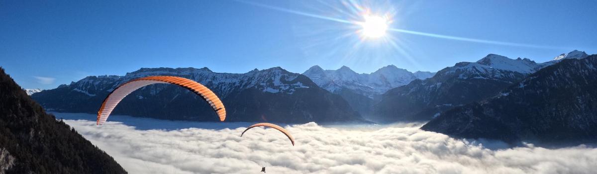 Dva paraglajdera lete nebom iznad planina