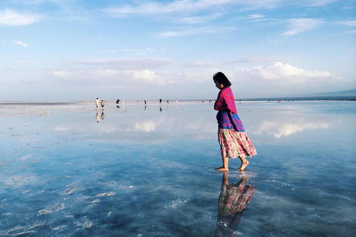 a woman walking in the water on the beach