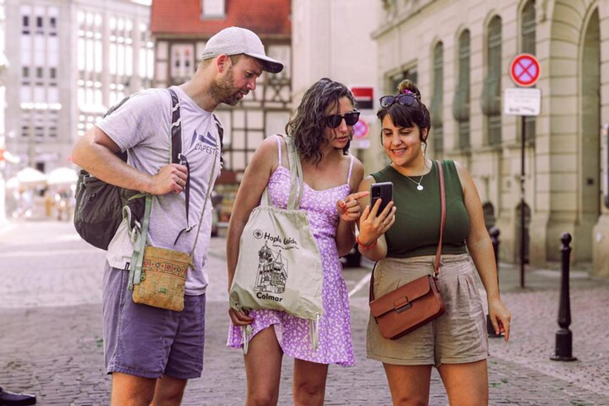 tre persone in piedi per strada che guardano un cellulare