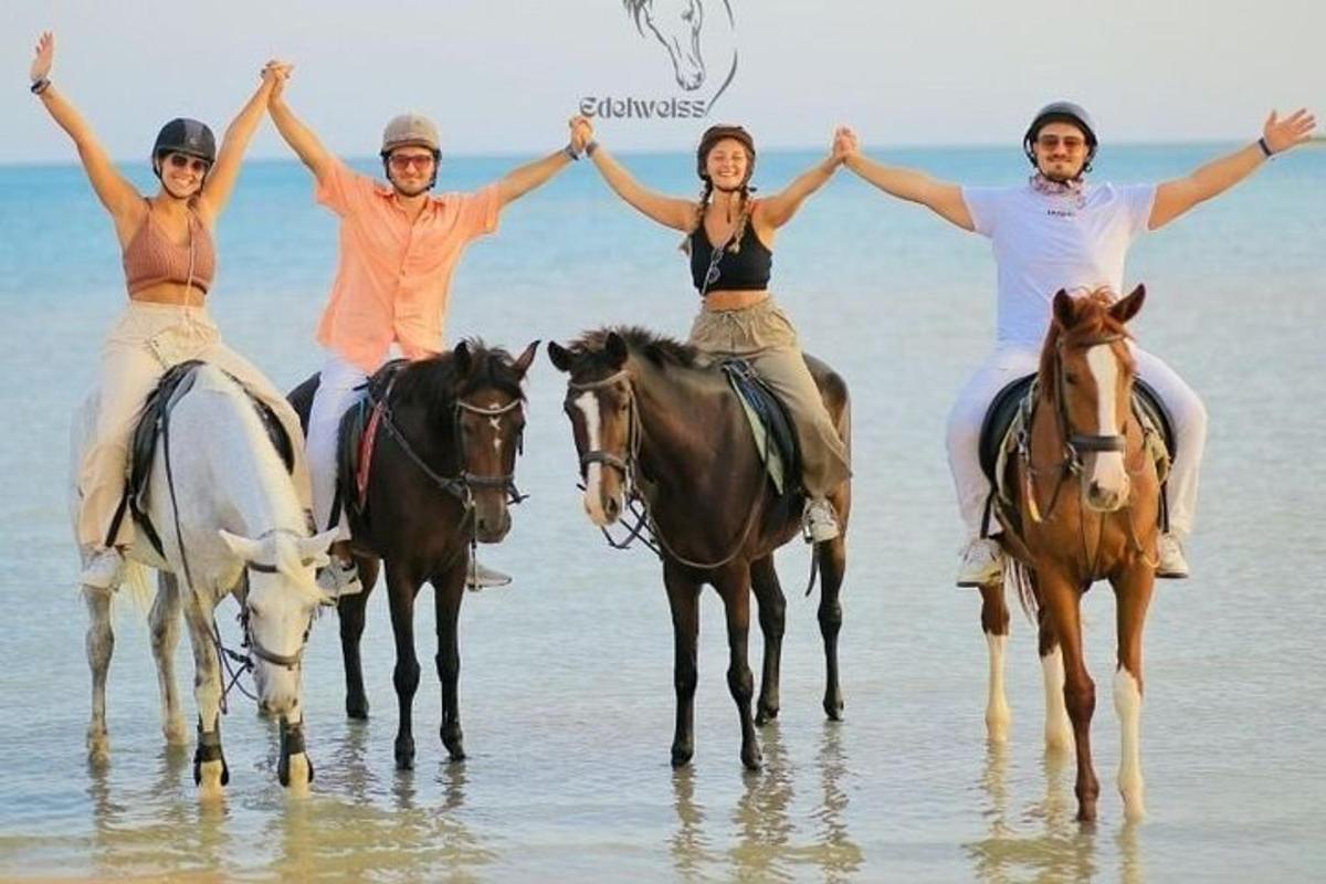 a group of people riding horses on the beach