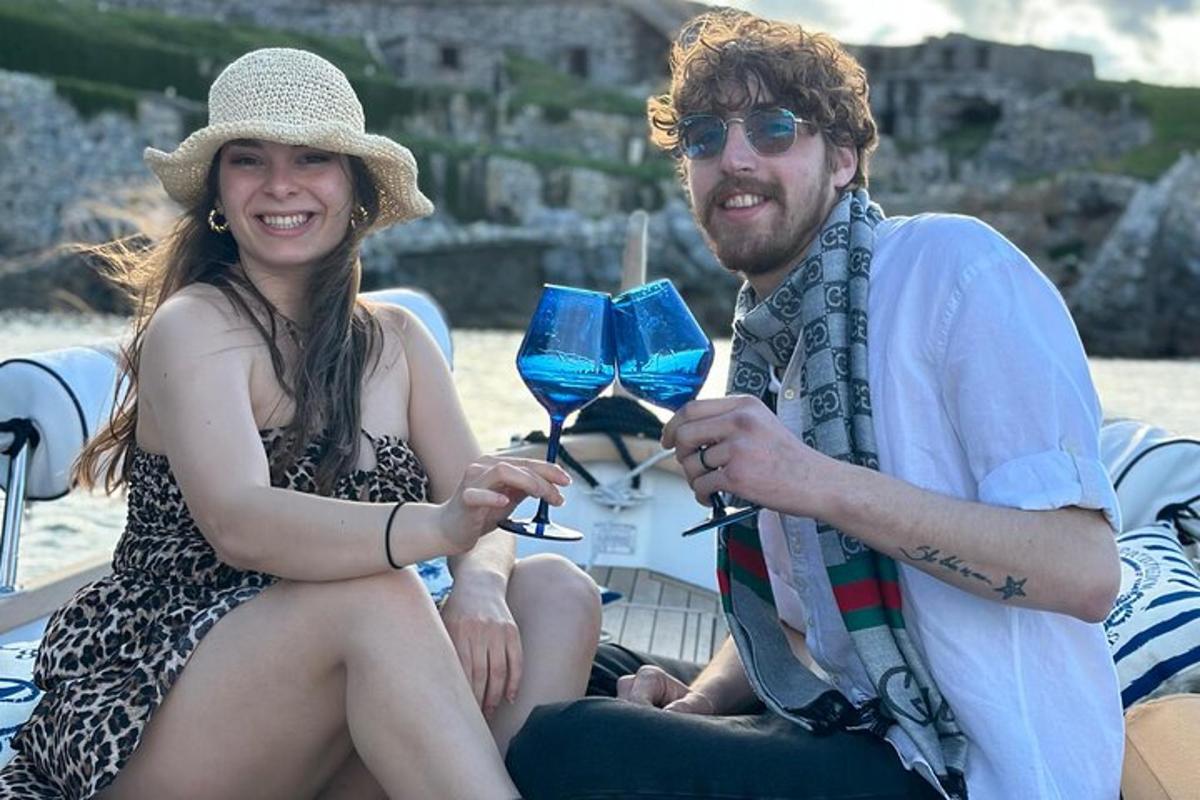 ein Mann und eine Frau sitzen mit Weingläsern auf einem Boot