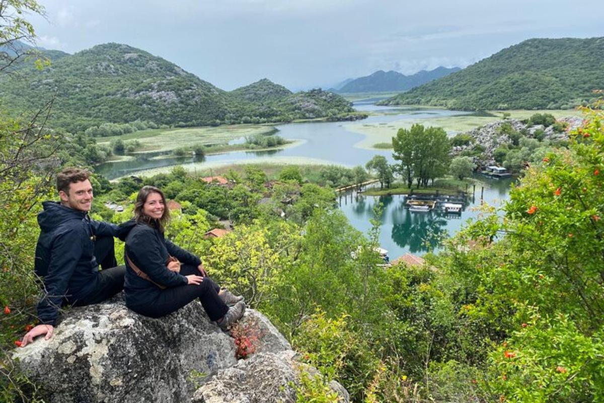 a man and woman sitting on a rock overlooking a river