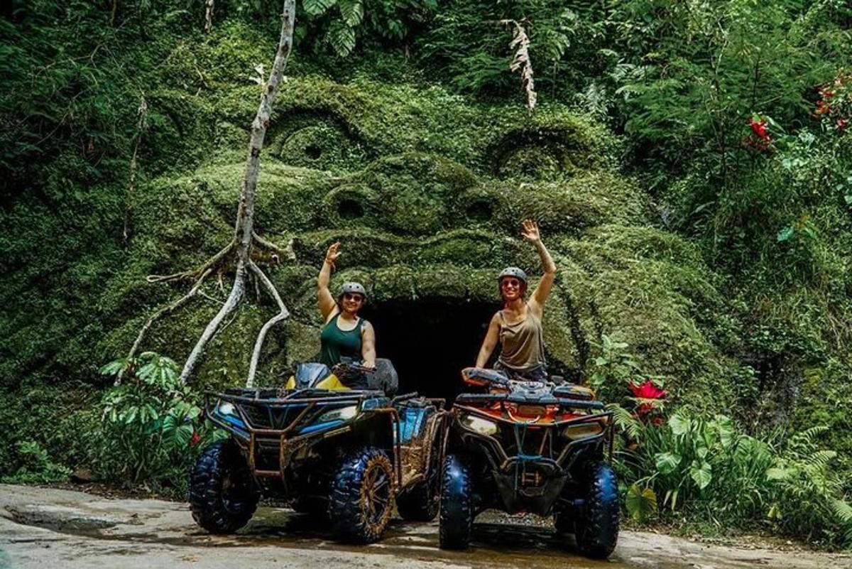 Două persoane stând pe ATV-uri cu mâinile în aer