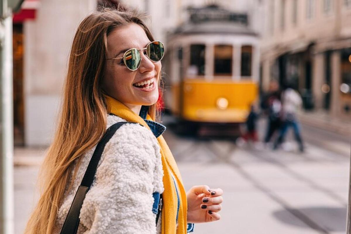 a woman wearing sunglasses standing on a street with a tram