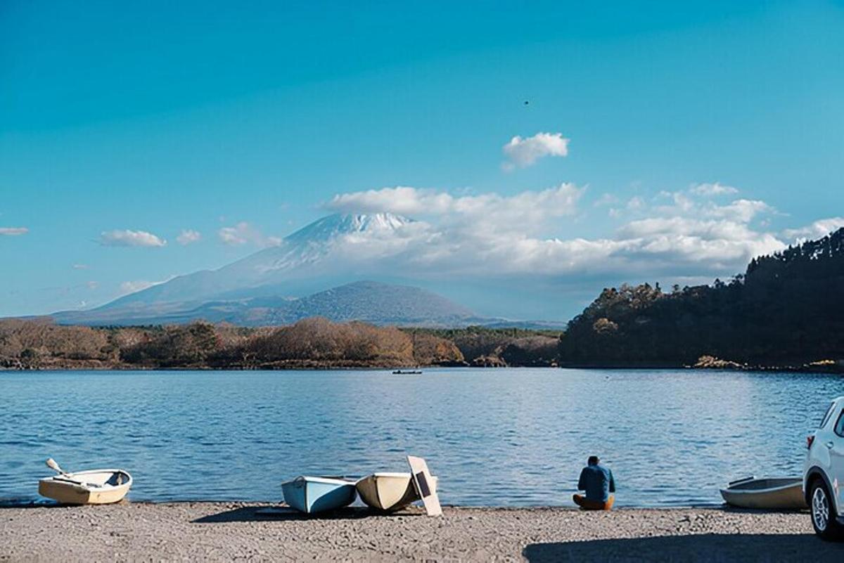 un uomo seduto sulla riva di un lago con delle barche