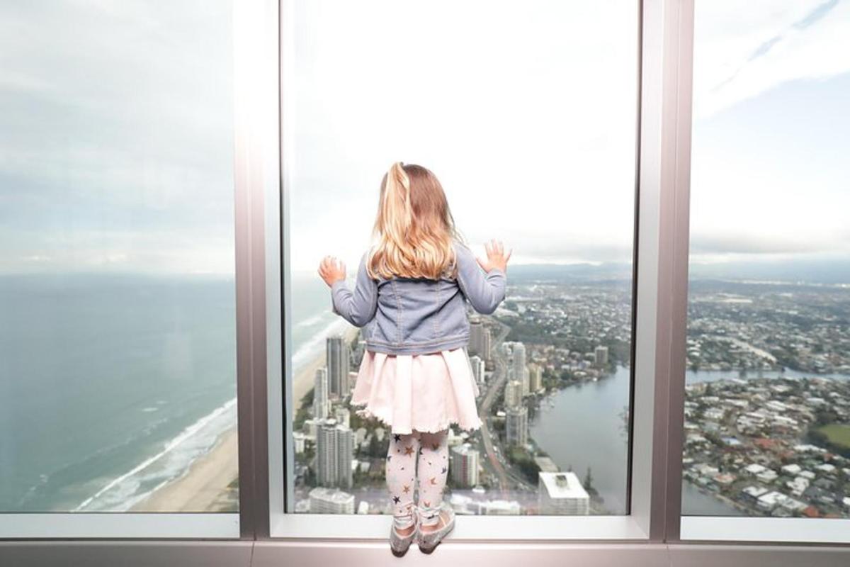 a little girl is standing on the edge of a window