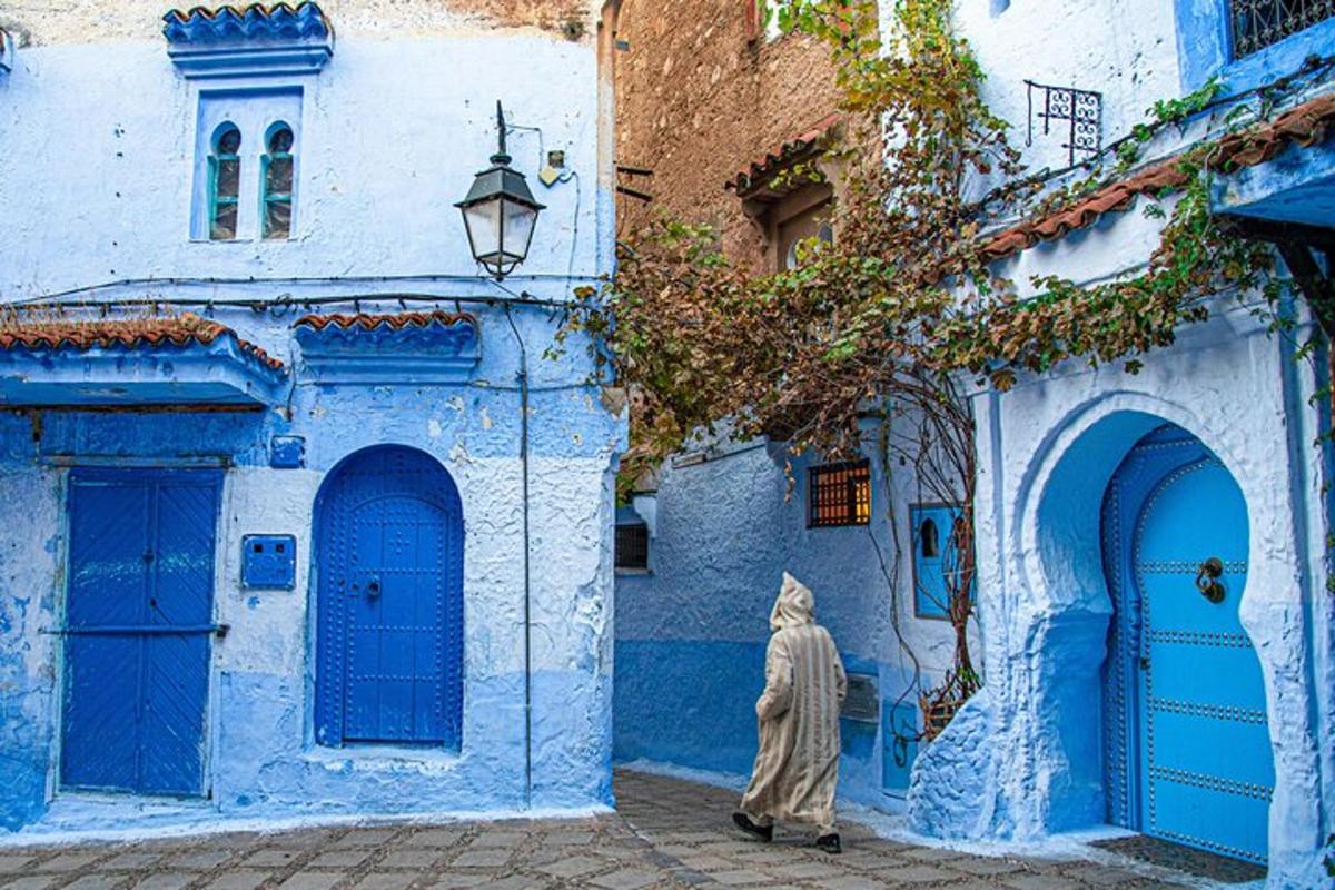 a woman walking down a street in front of blue buildings