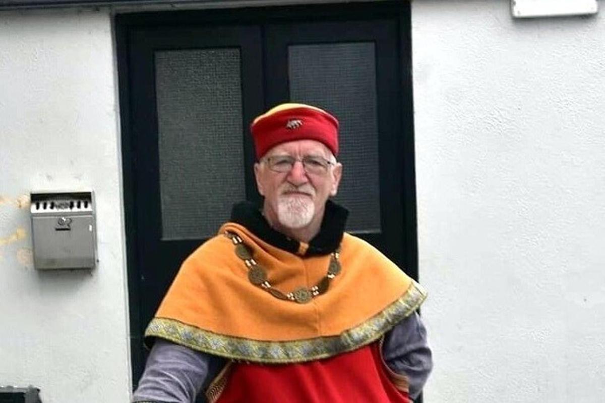 an older man dressed as a priest standing in front of a door