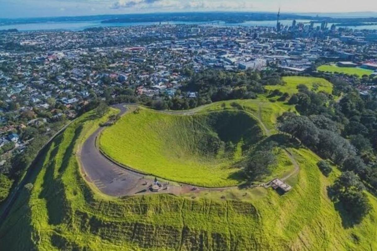 an aerial view of a green hill with a city