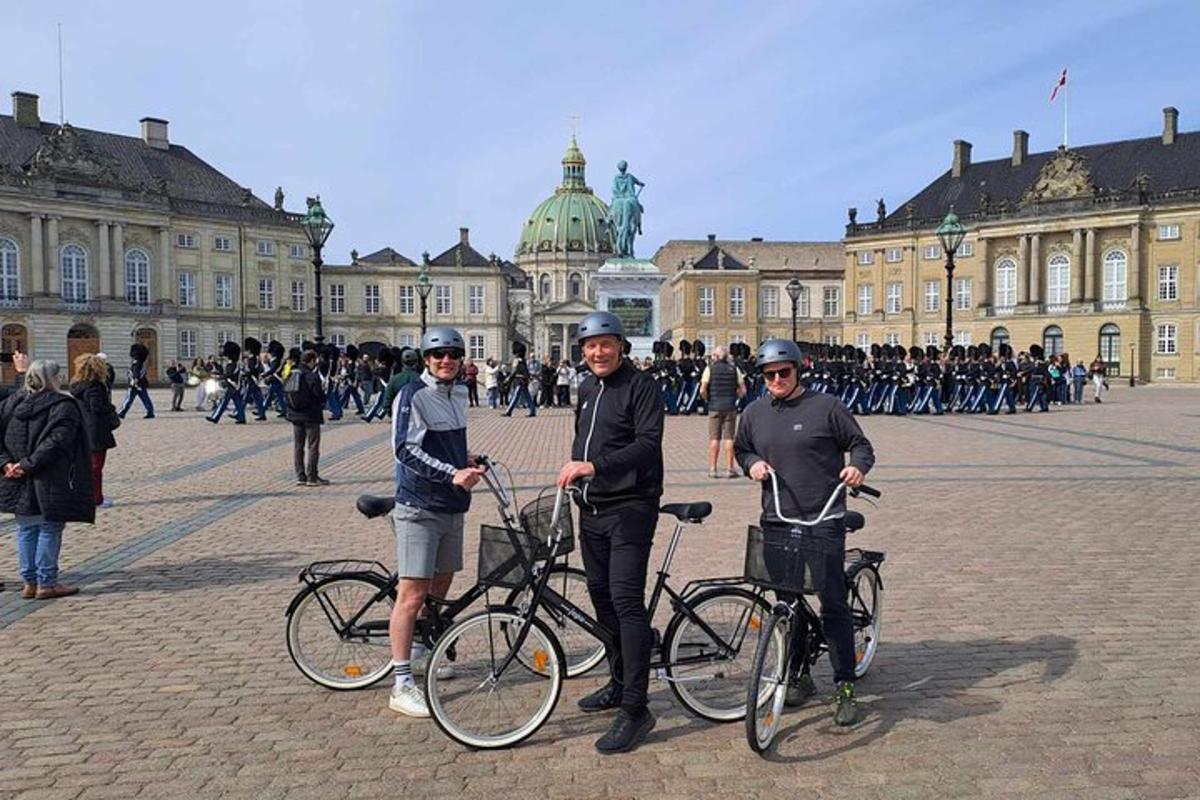 Þrír einstaklingar standa með hjól fyrir framan byggingu