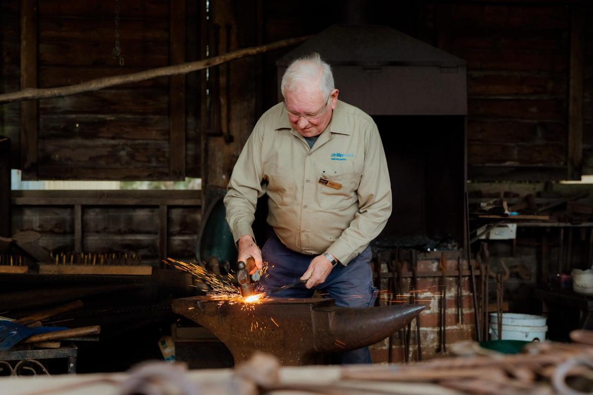 an older man cutting a piece of metal in aauldron