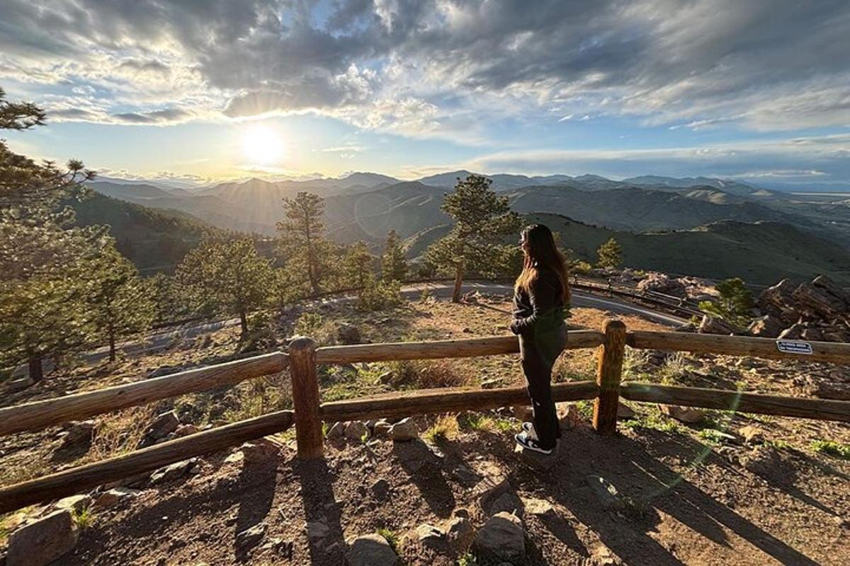 a woman standing on a fence looking at the mountains