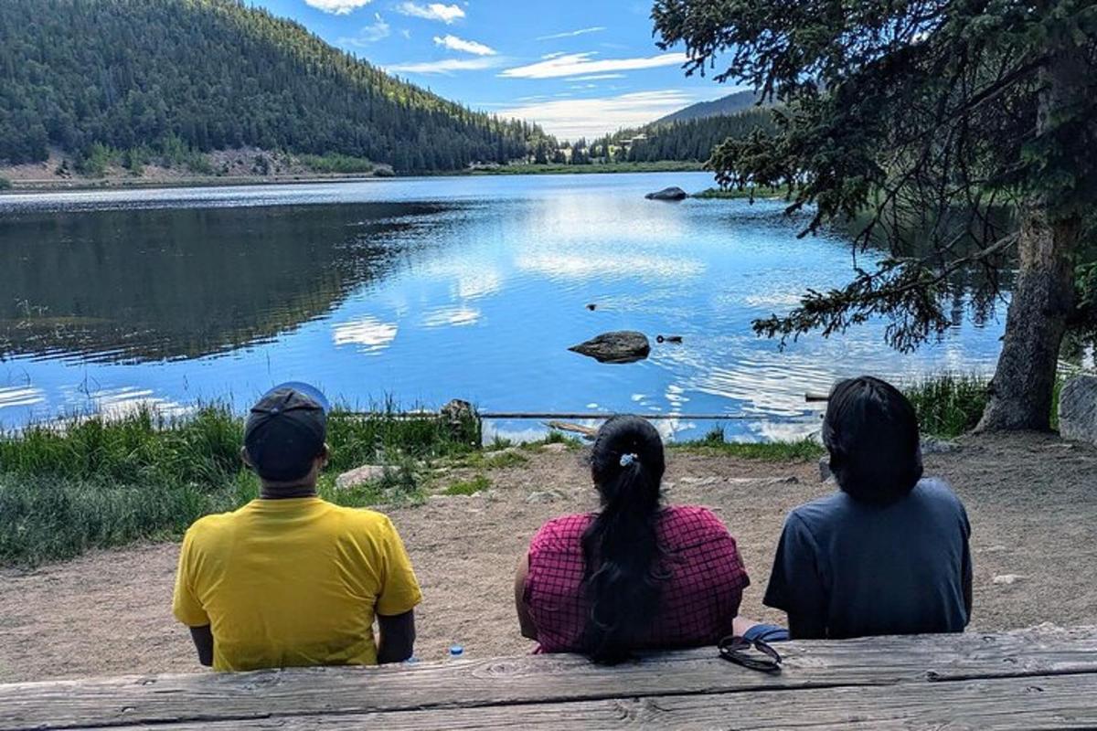 three people sitting on a bench looking at a lake
