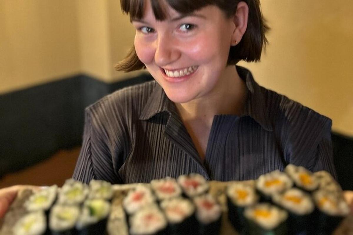 uma mulher está sorrindo ao lado de uma bandeja de sushi