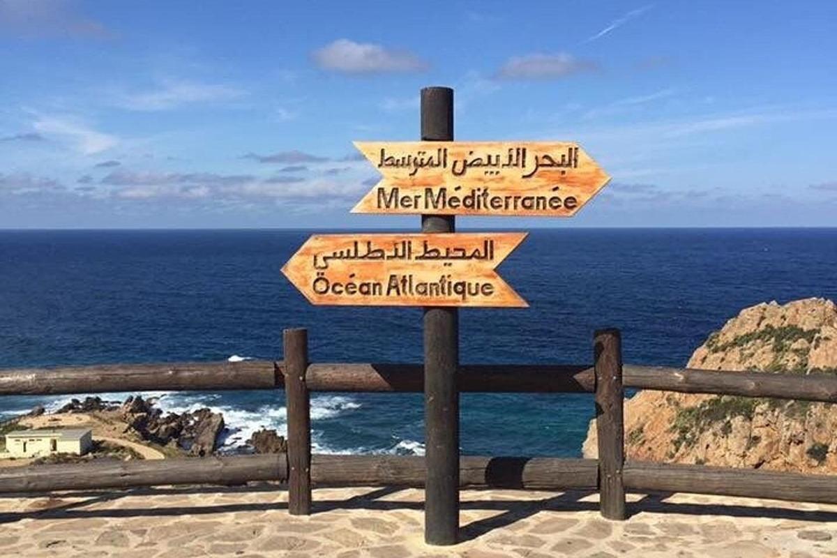 uma placa com setas na praia com o oceano