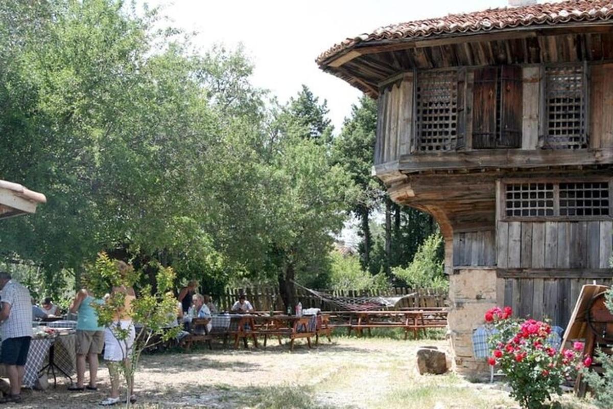skupina ljudi, ki sedijo za mizami pred stavbo