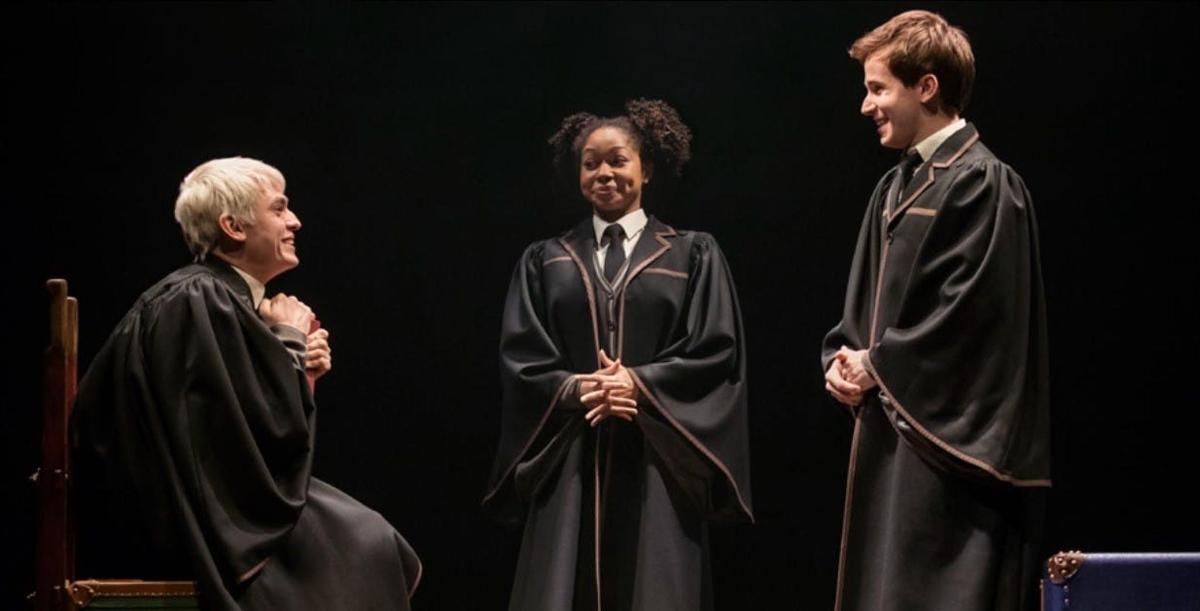 Un grupo de tres personas con togas negras de graduación.