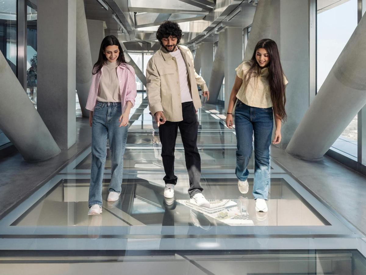 three people walking on the glass floor of an elevator