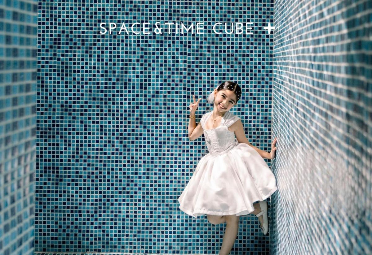 a young girl in a white dress leaning against a wall