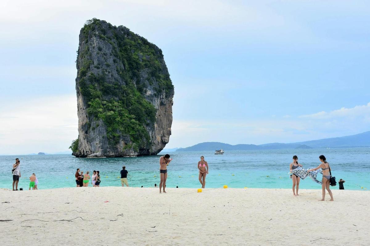 a group of people on a beach with a large rock