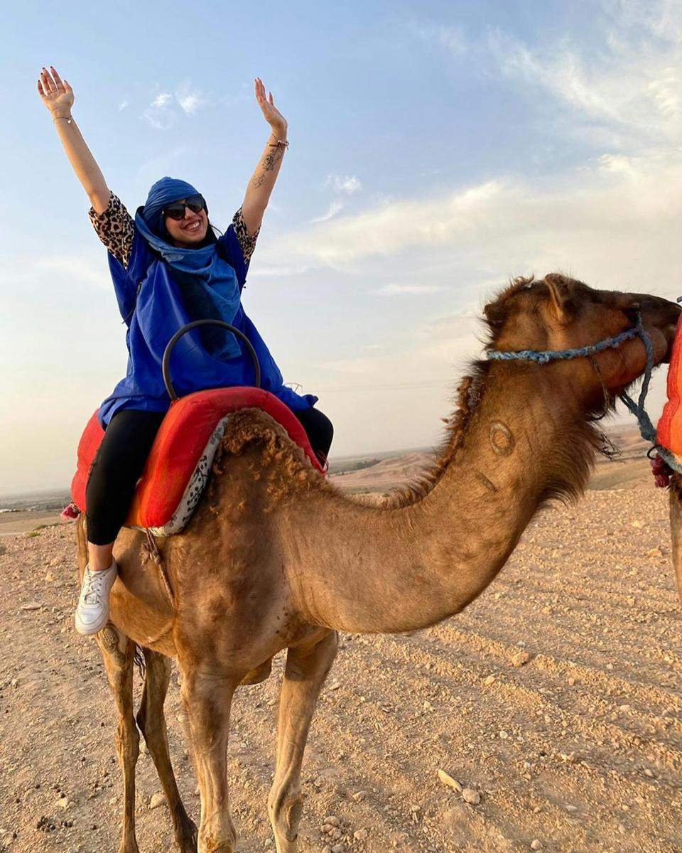 eine Frau, die auf einem Kamel in der Wüste reitet